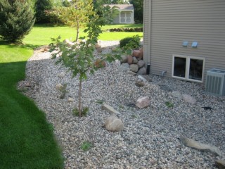 River rock with medium and small boulders and boulder retaining wall